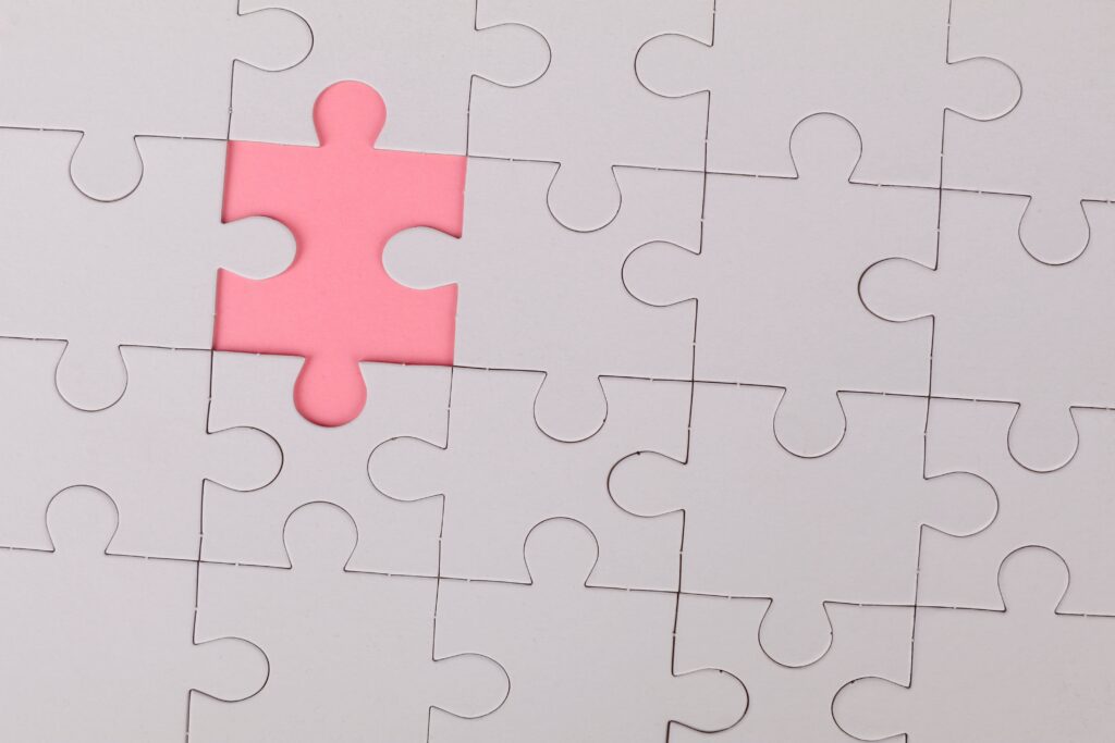 White jigsaw puzzle with a missing piece on a pink background.
