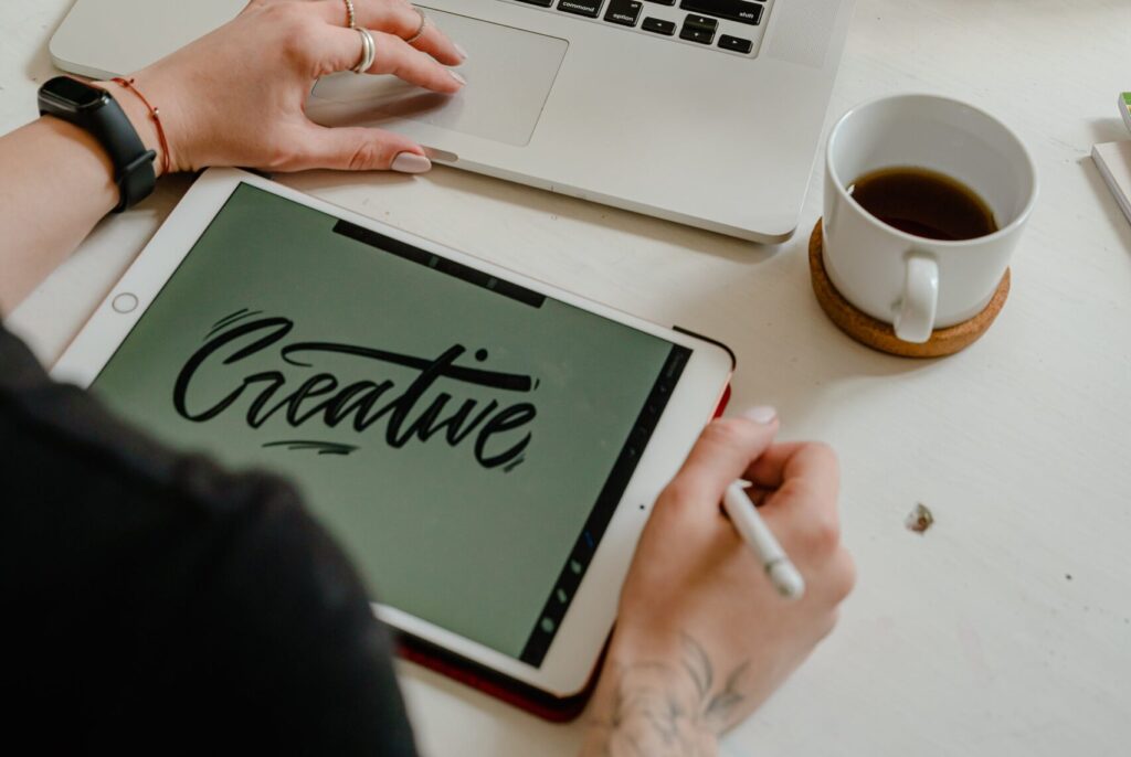 Person Using Macbook Pro and iPad to design a graphic.