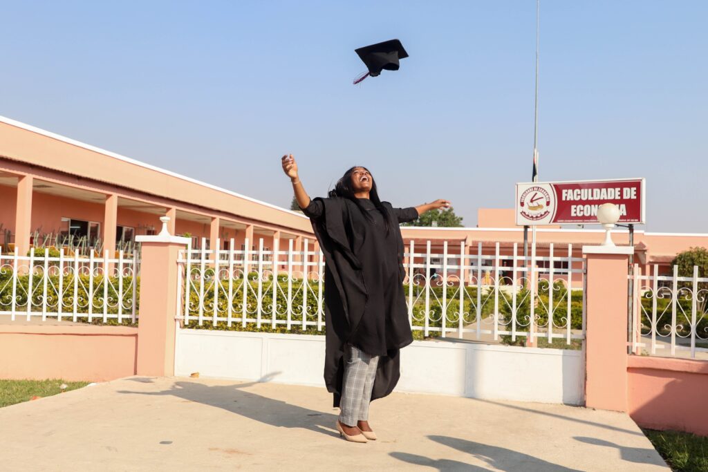 Woman joyfully throws her graduation hat in the air after successfully completing her studies at a university.