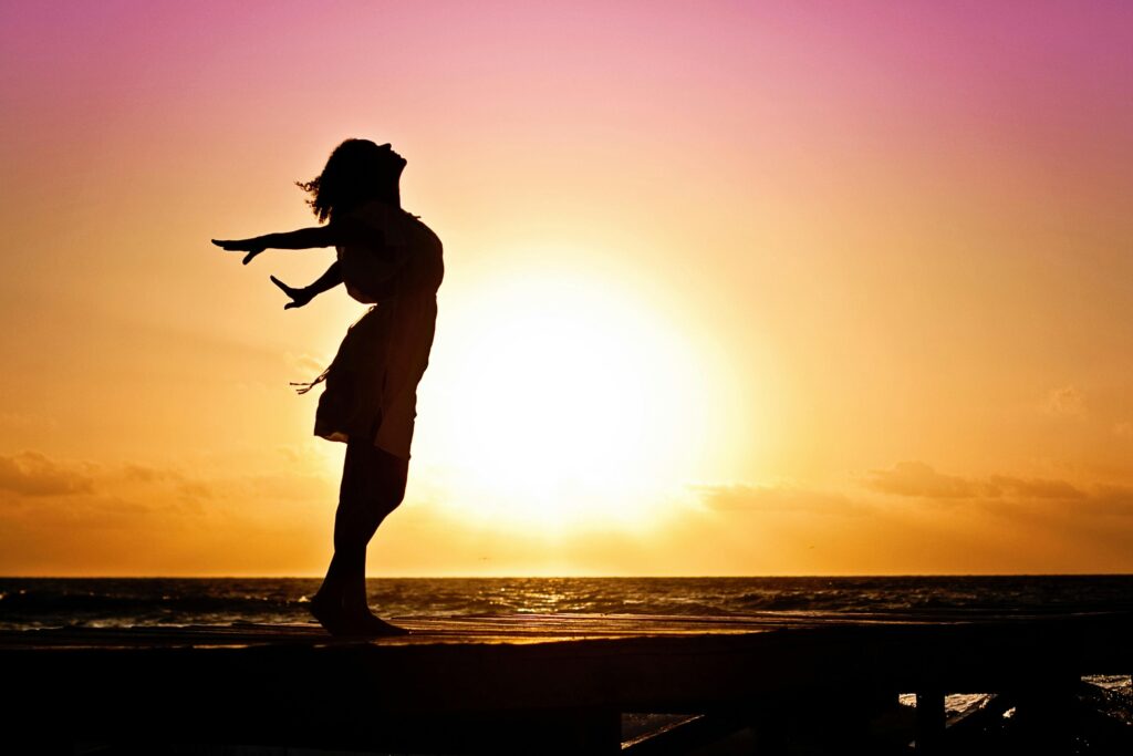 Confident lady in beach silhouette at sunrise, exuding freedom and strength.