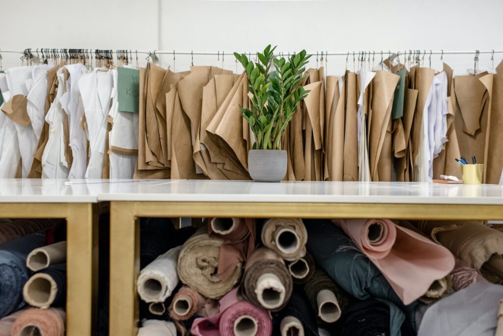 Rolls of assorted fabrics, textiles, and sewing patterns inside workshop.