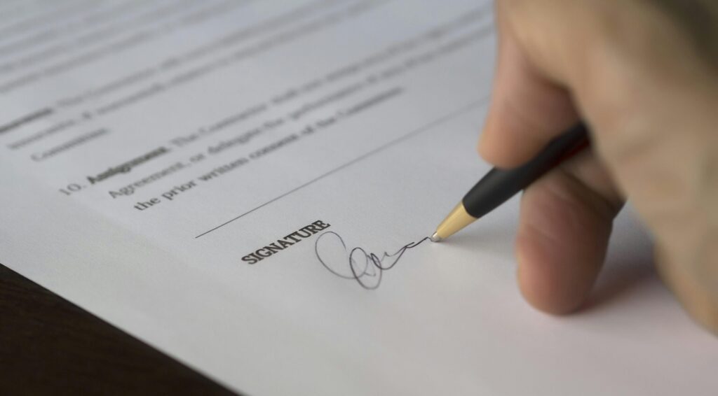 Close-up of person signing their signature on a legal document.