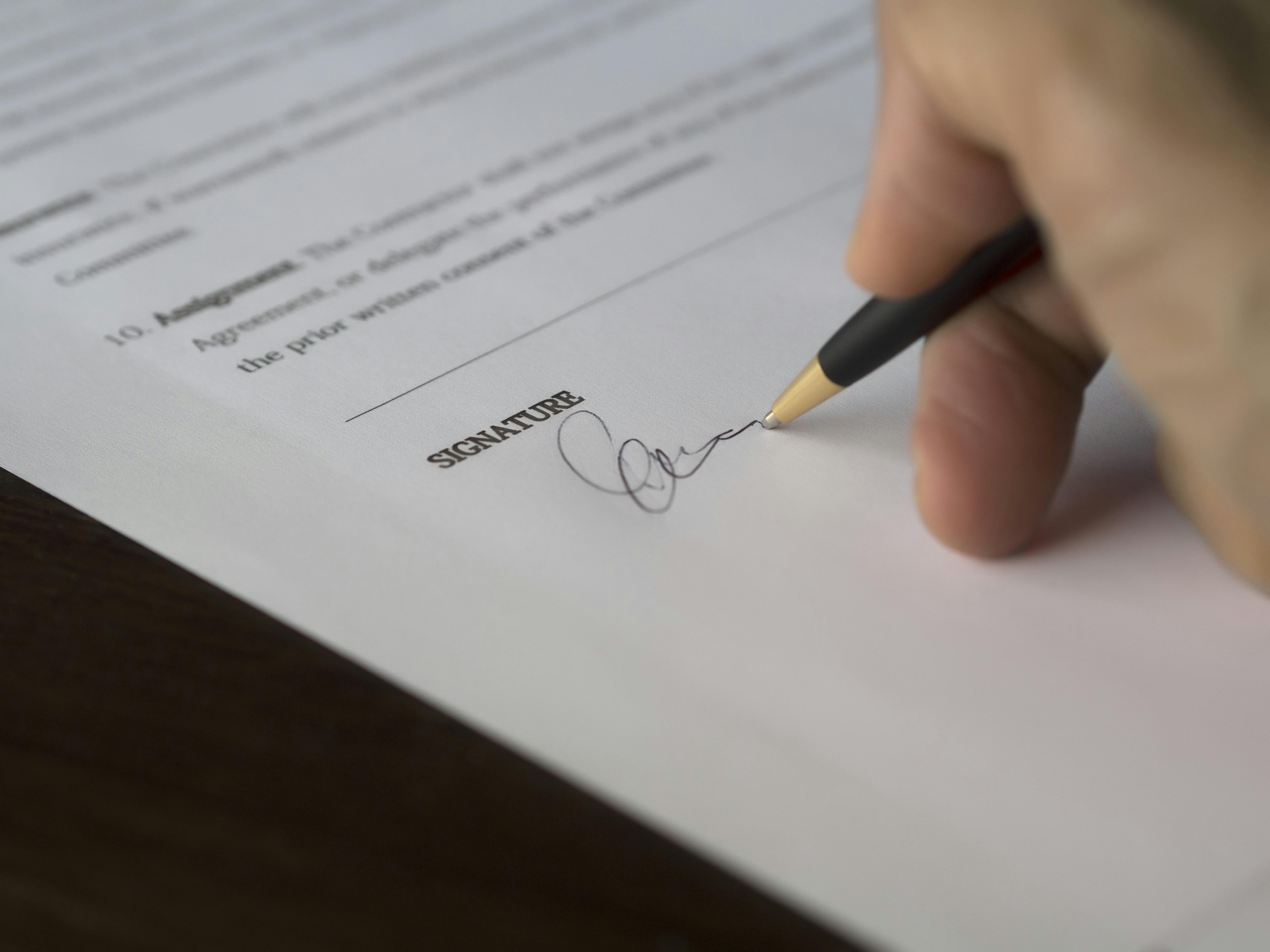 Close-up of person signing their signature on a legal document.