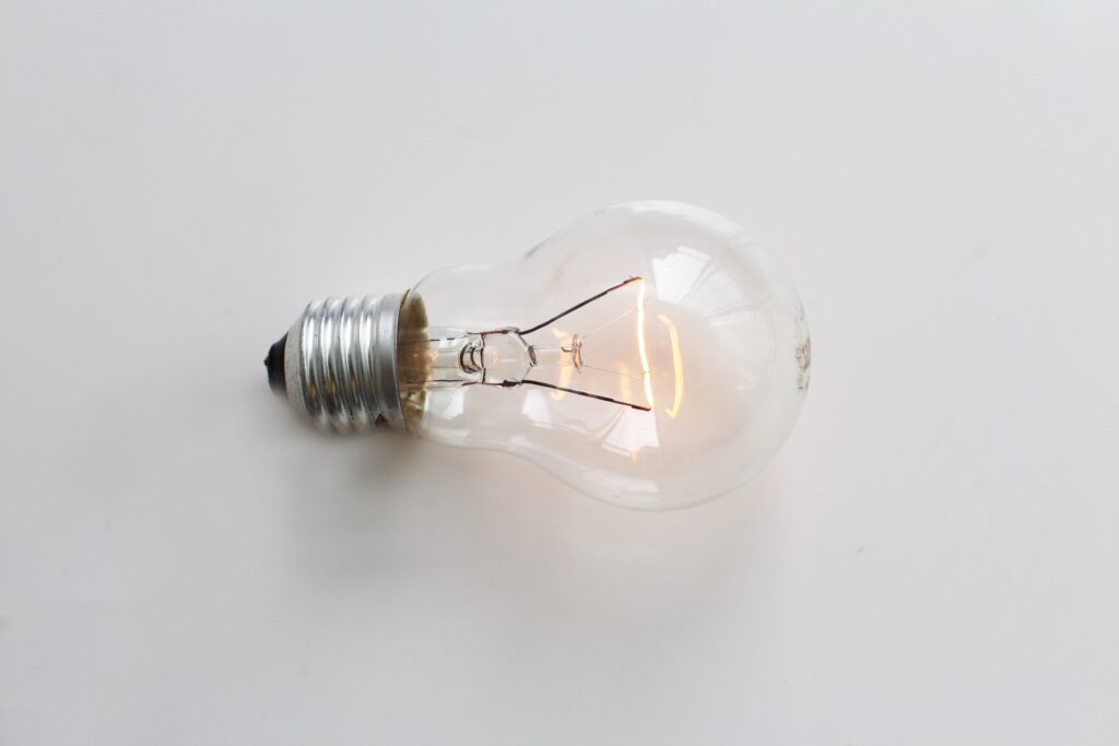 Illuminated light bulb on white surface, symbolizing idea generation.