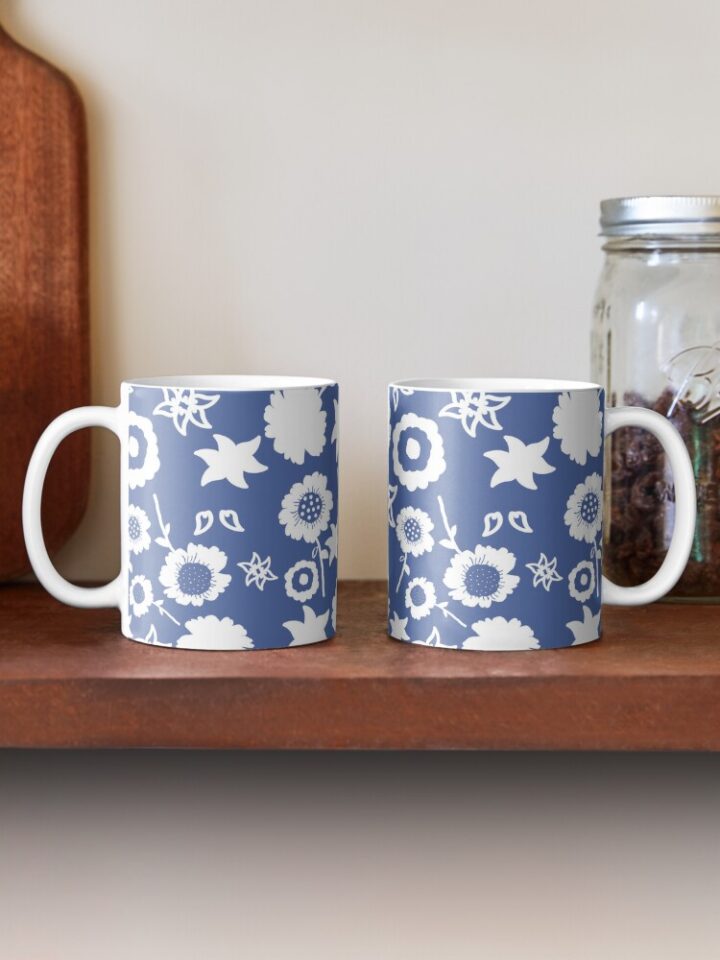 Two ceramic flower mugs featuring a wraparound blue and white floral pattern design. Designed by Zuzanii Designs.