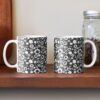 Two ceramic flower mugs featuring a wraparound black and white floral pattern design. Designed by Zuzanii Designs.