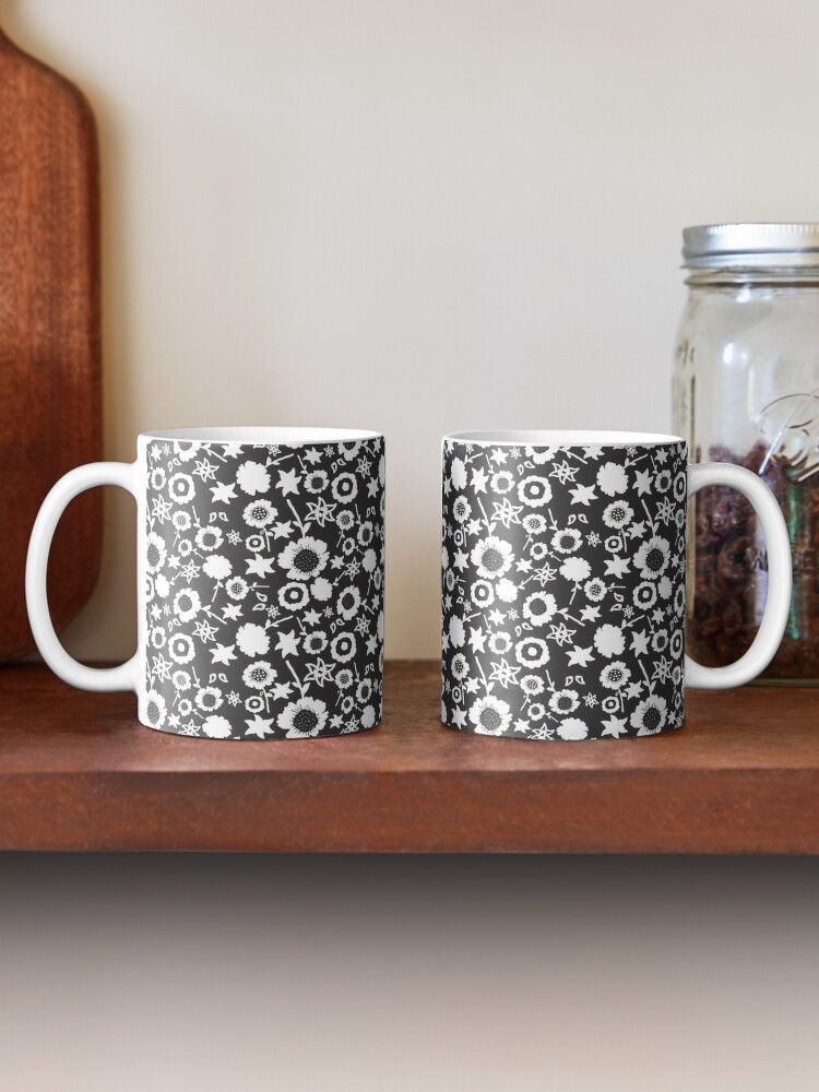 Two ceramic flower mugs featuring a wraparound black and white floral pattern design. Designed by Zuzanii Designs.